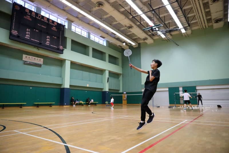 A player prepares to serve on an indoor badminton court
