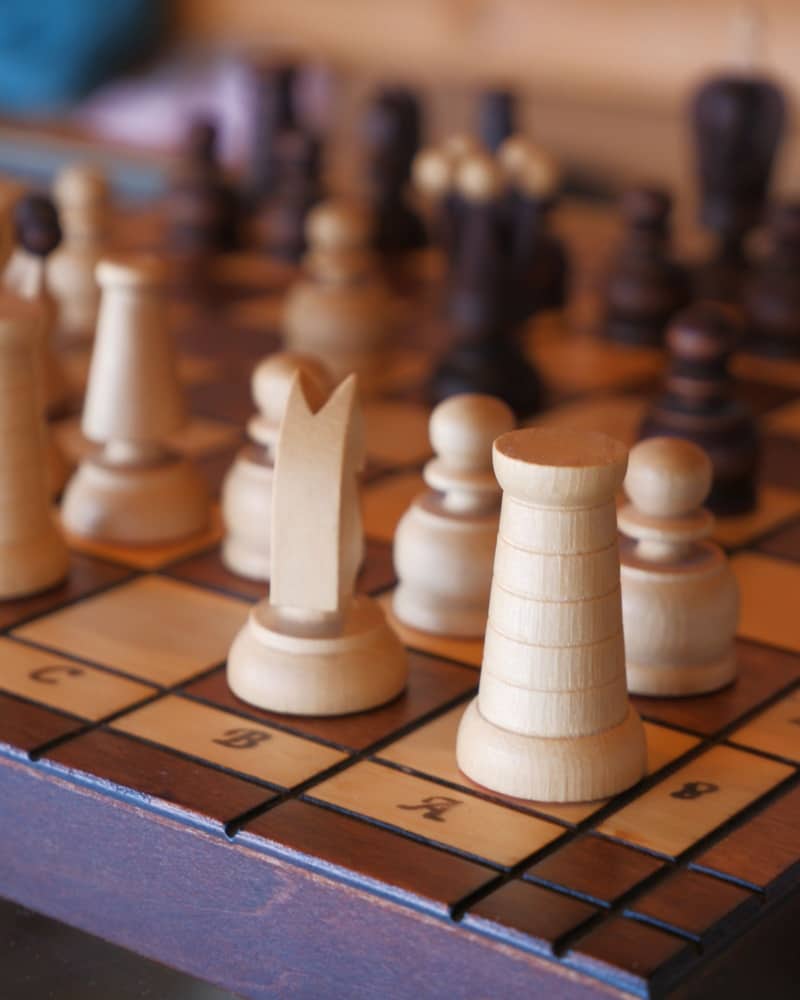 A wooden chessboard mid-game, pieces caught in the middle of a position